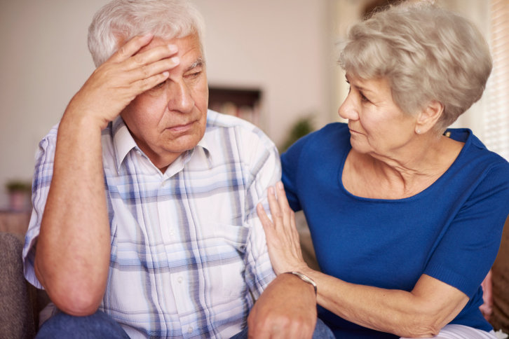 Elderly-couple-sitting-on-couch-stressed